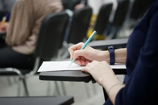 a girl writes a dictation or fills out documents in the audience sitting on a school chair